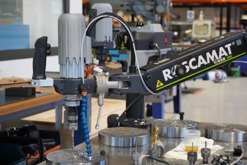 Roscamat electric articulated tapping arm executing high-precision automatic tapping on a metal plate.